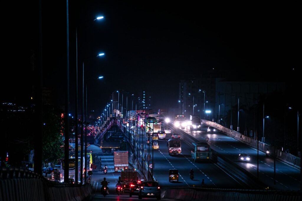 Evening traffic on a road in Greater Accra with headlights and streetlights