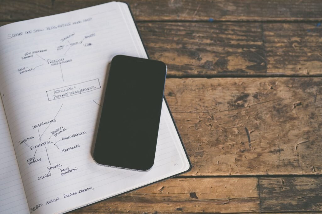 Someone reviewing travel and timing notes beside a phone on a table