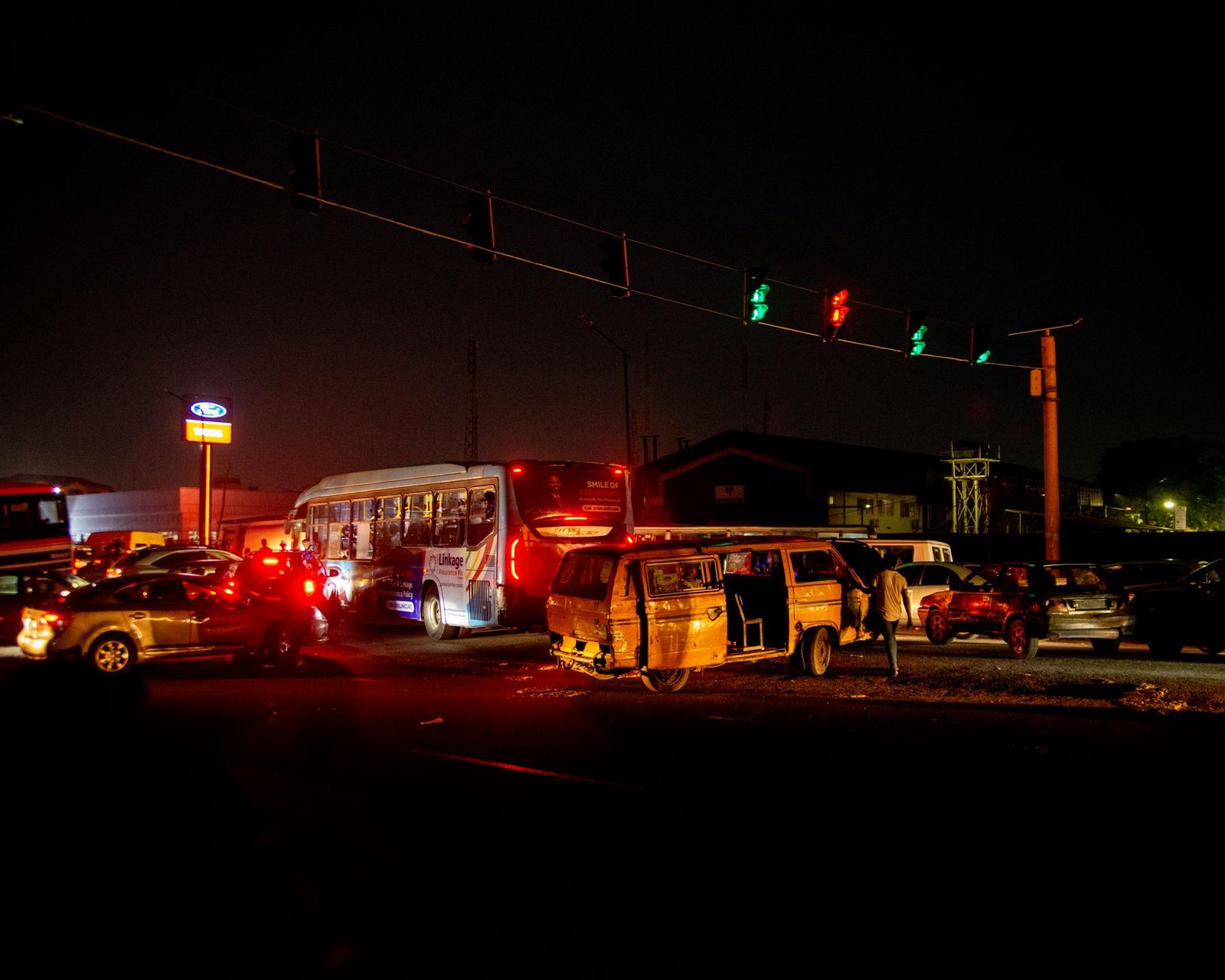 A crowded urban nighttime scene featuring a traffic accident at a busy intersection.