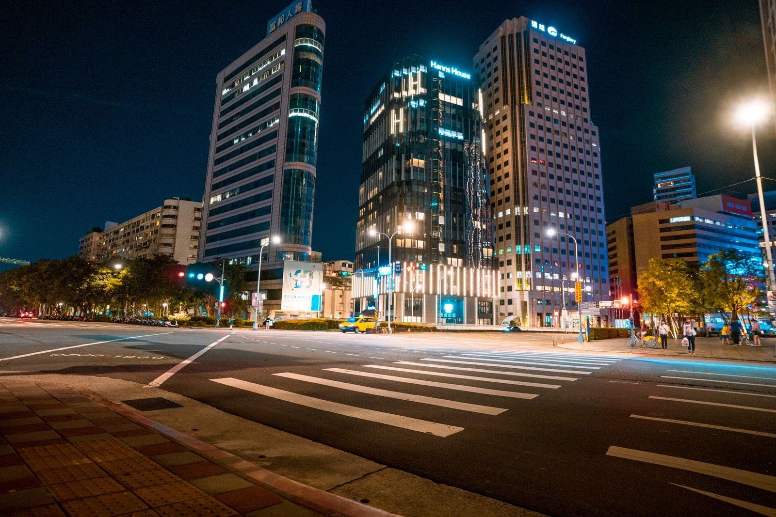 Dynamic cityscape featuring illuminated high-rise buildings and lively streets at nighttime.