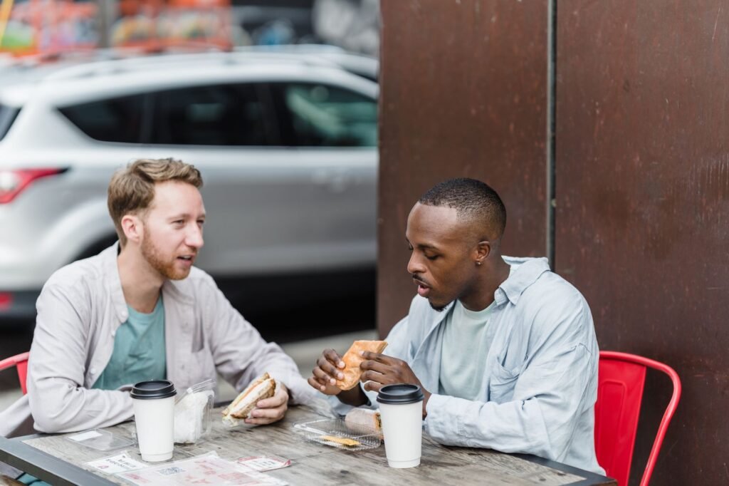 Two adults talking over food at an outdoor table in the evening