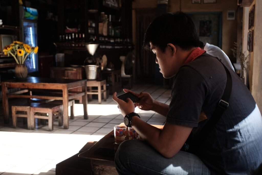 Adult looking thoughtfully at a smartphone indoors in warm light