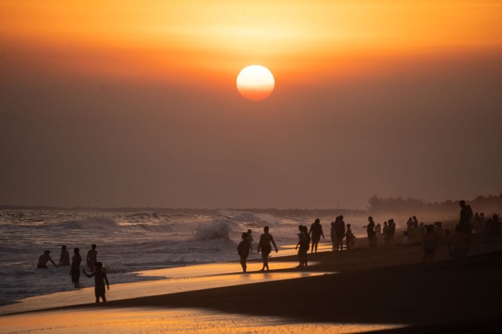People enjoying the ocean at sunset on Monterrico Beach, Guatemala.