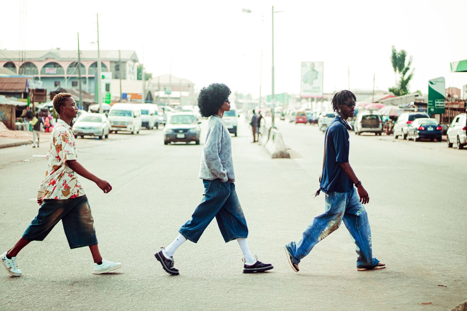 Three young adults walking across a sunny city street, embracing the summer vibe.