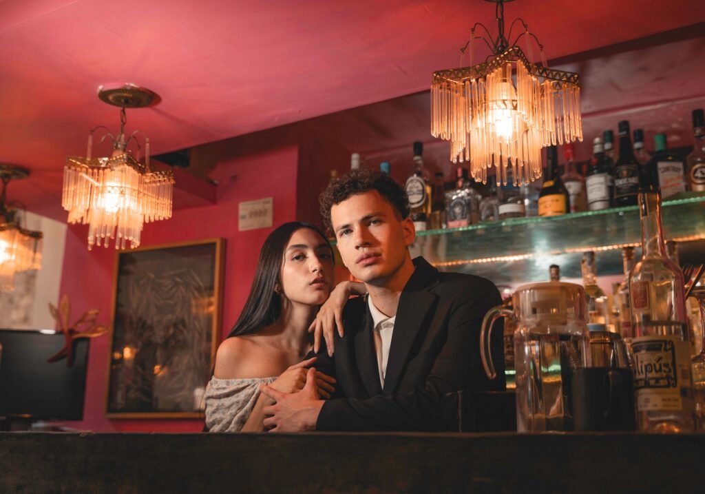 Young couple posing elegantly at a vibrant bar with ambient lighting. Perfect nightlife vibe.