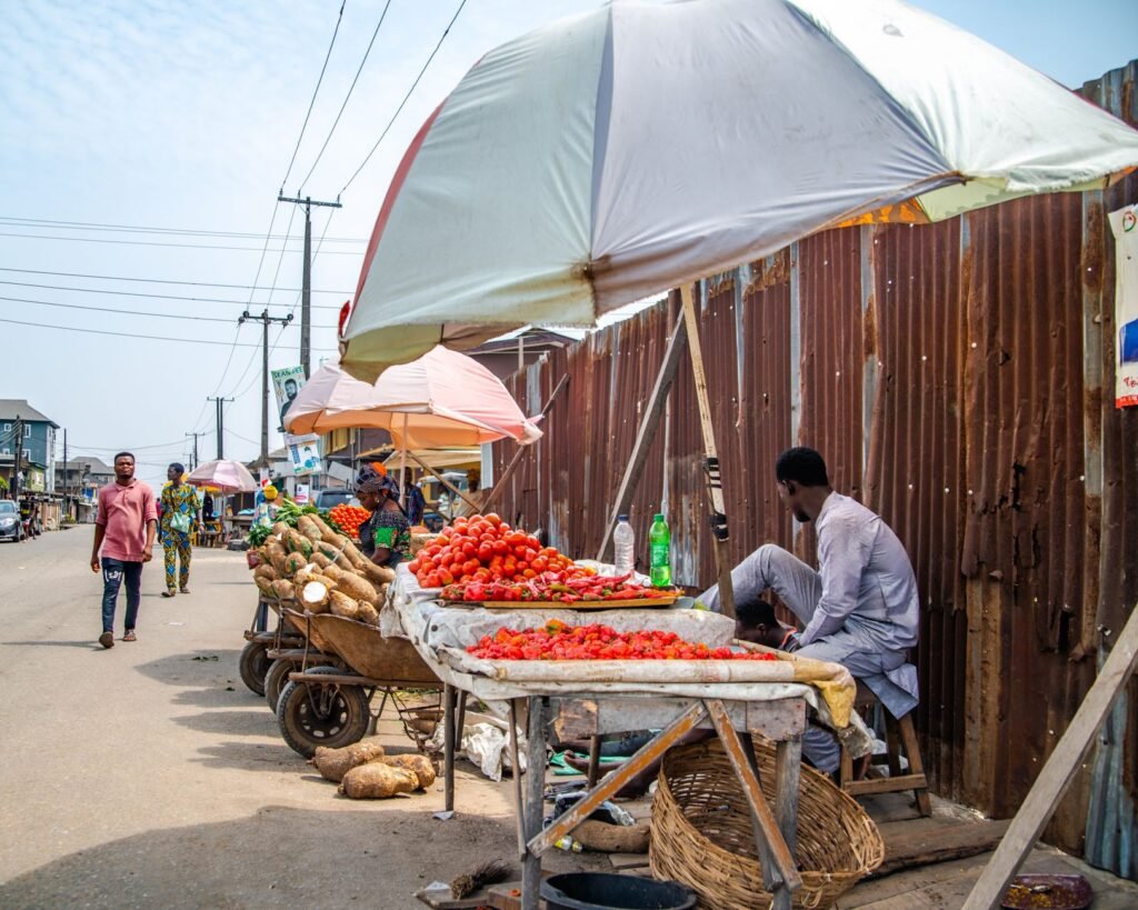 A bustling street market in Lagos selling fresh produce under colorful umbrellas.