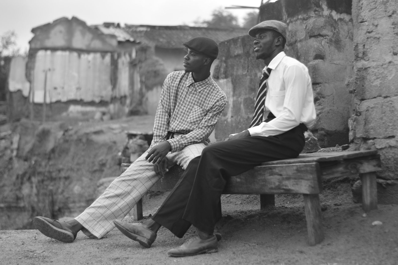 Two men sitting on a bench in Sekondi-Takoradi, Ghana, in a vintage black and white style.