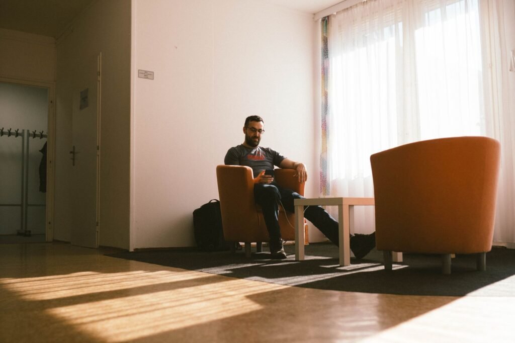 Man checking his phone outside a softly lit lounge in the evening