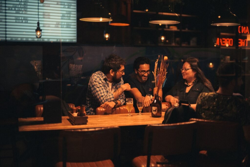 Two adults in relaxed conversation at a warmly lit Ghanaian bar