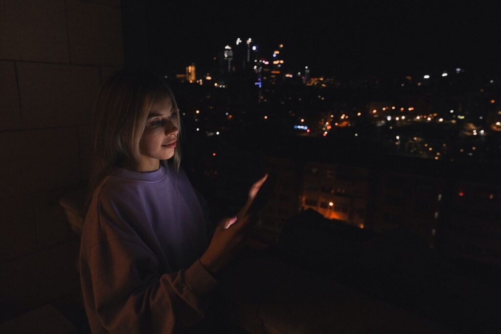 A person using a smartphone in the evening to browse profiles discreetly