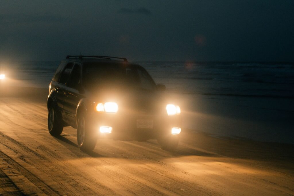 Night drive along a coastal road with headlights and dashboard glow