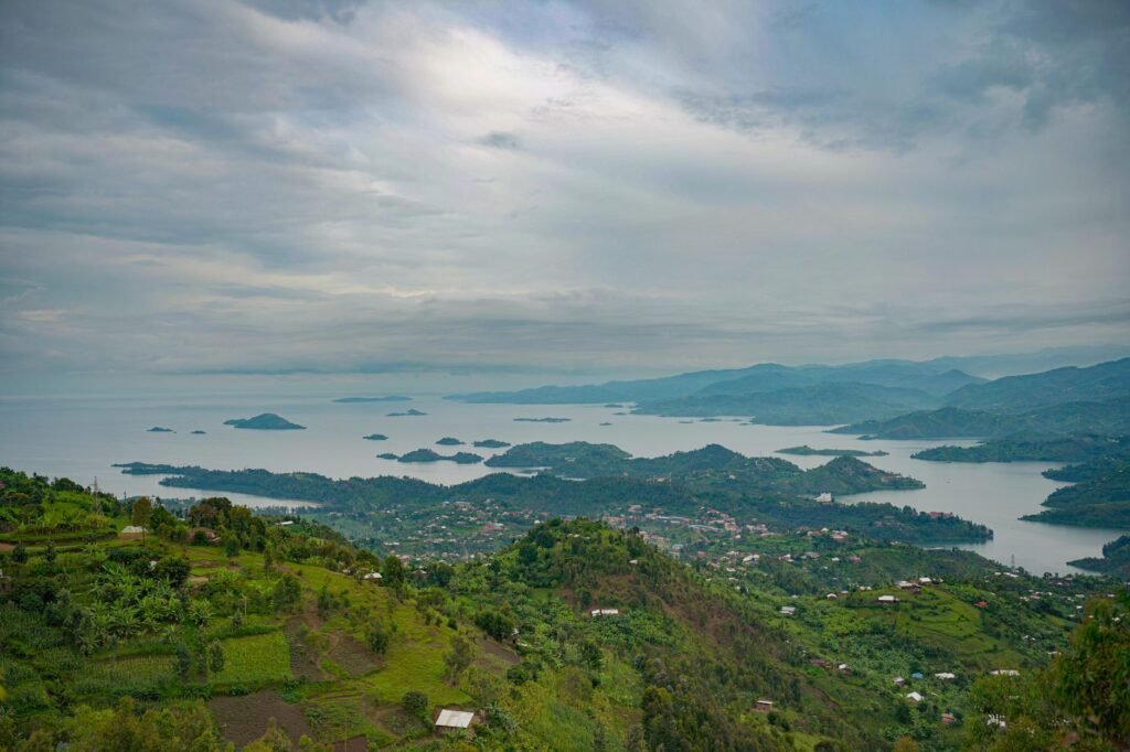 A breathtaking view of a lake with scattered islands and lush green landscapes under a cloudy sky.