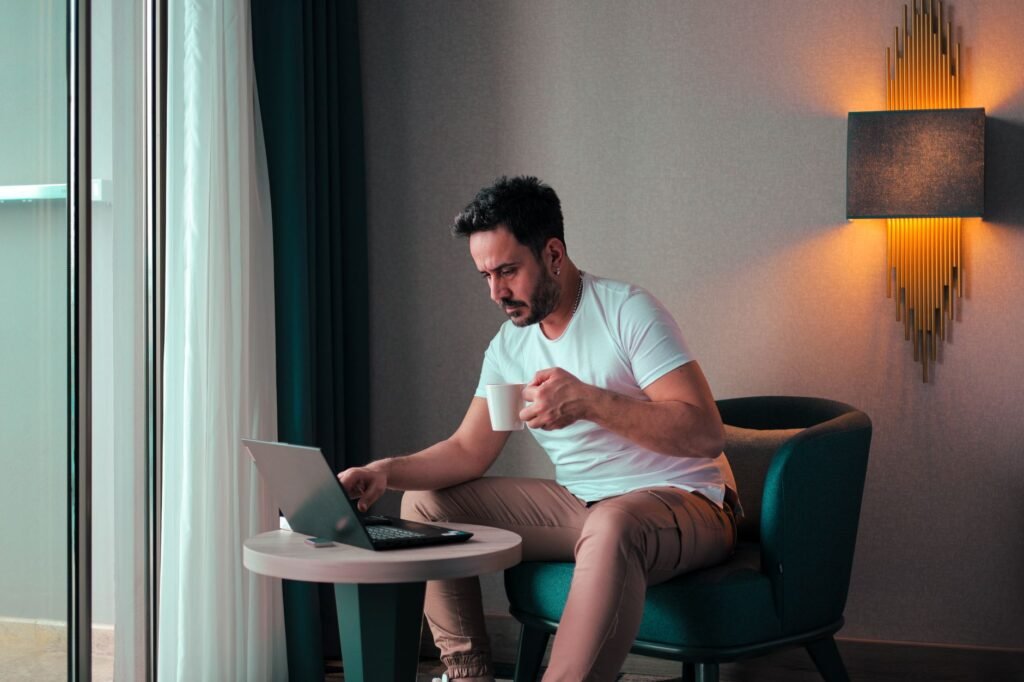 A person browsing profiles on a laptop in a softly lit hotel room