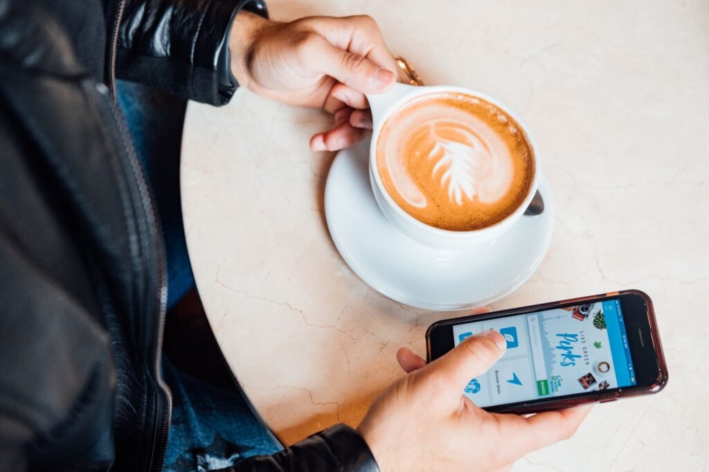 A person browsing listings on a smartphone at a cafe table in daylight