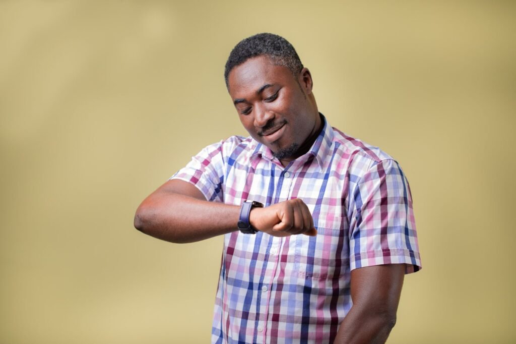 Portrait of a man checking his wristwatch, set against a yellow background, conveying a sense of time awareness.