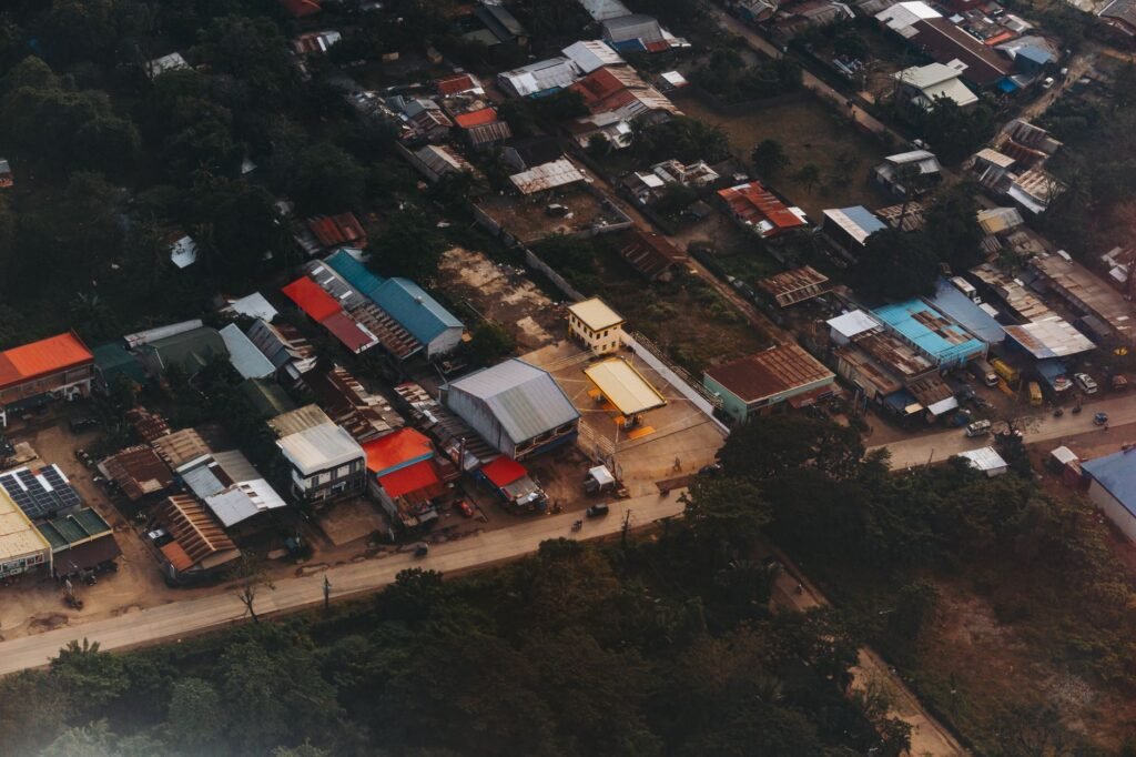 Aerial view showcasing rooftops and streets of a small bustling town, during the day.