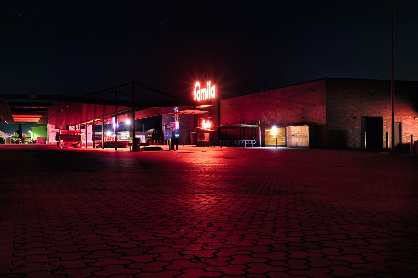 Night scene of an empty Famila supermarket with vibrant red lighting.