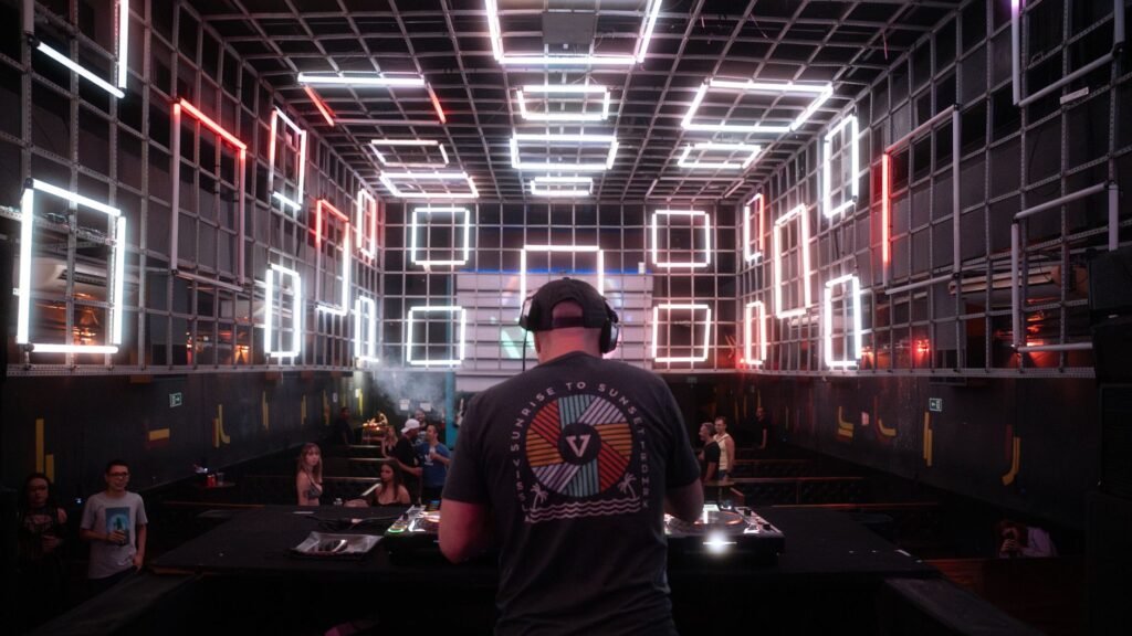 Dynamic DJ performance in a modern nightclub with glowing neon light installations.