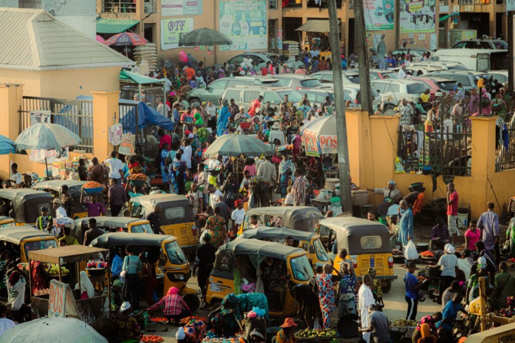 Bustling street market in Lagos, Nigeria with people and rickshaws.