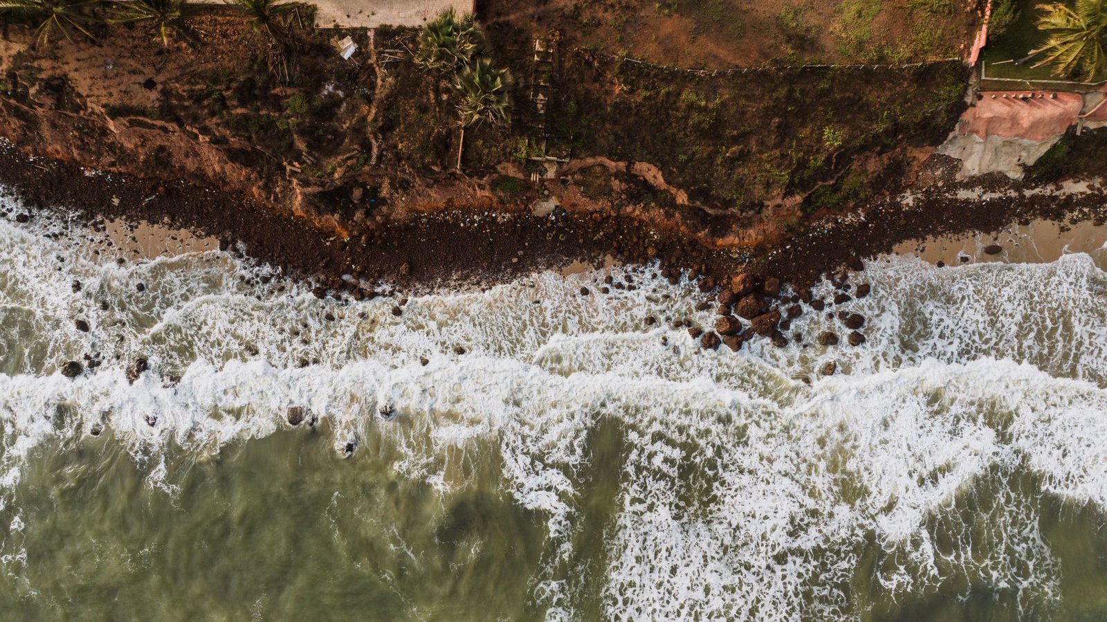 Drone shot capturing a dramatic view of ocean waves hitting a rocky coastline.