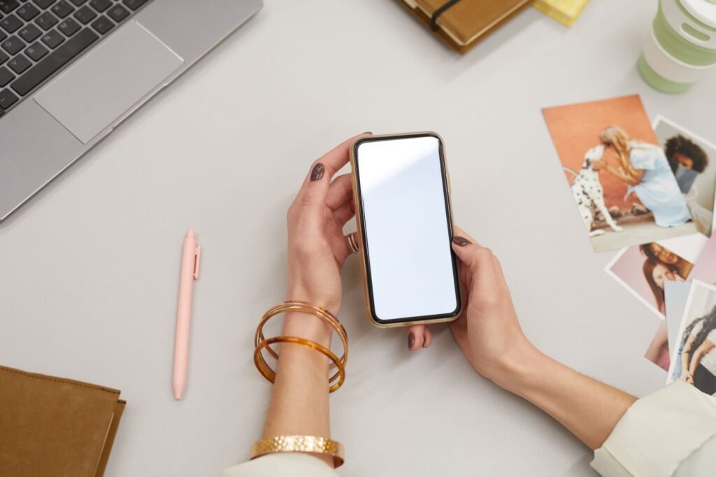 Person browsing listings on a smartphone at a desk with a notebook beside them