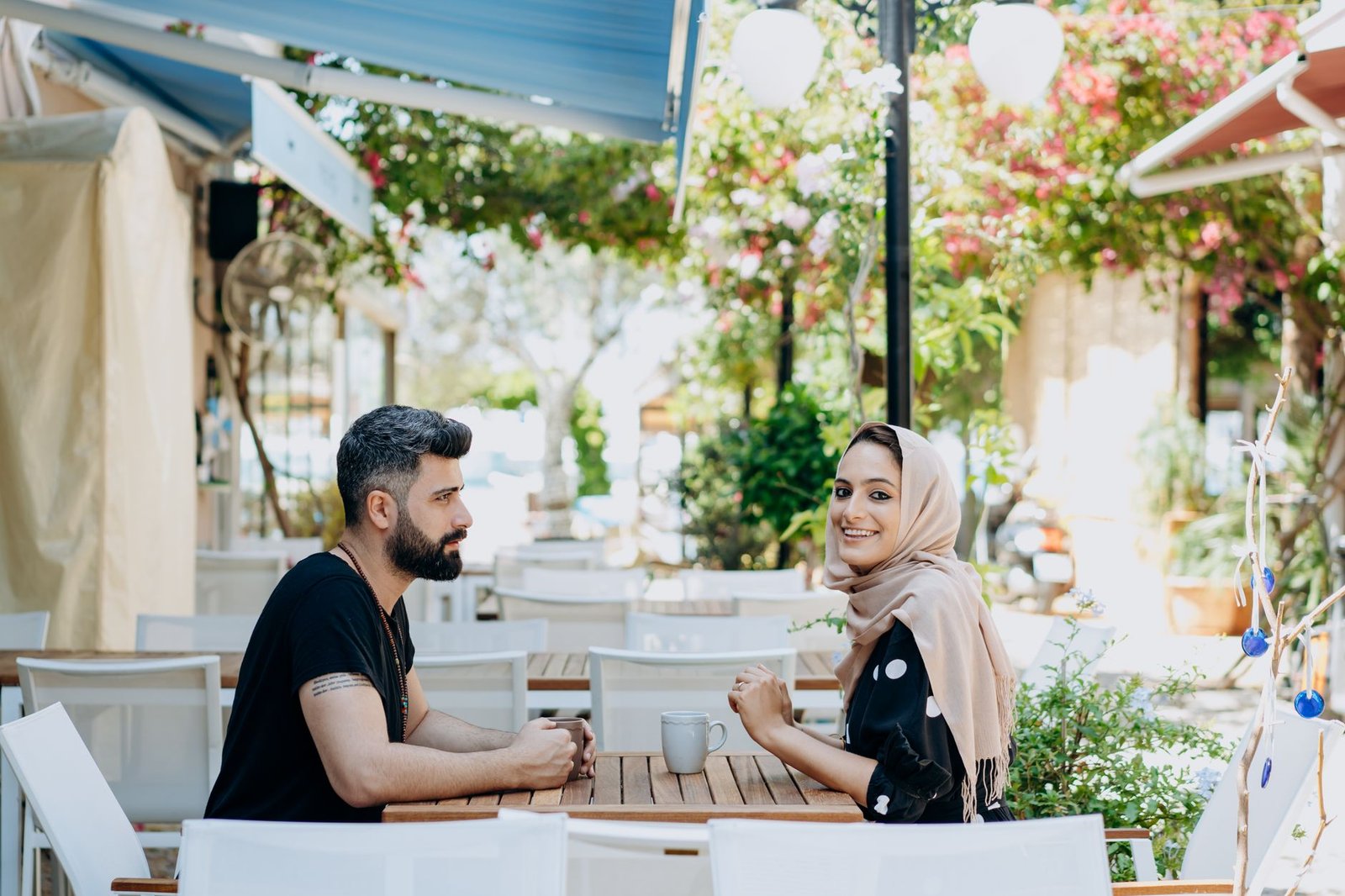 A couple enjoying coffee at an outdoor café on a sunny day, displaying warmth and romance.