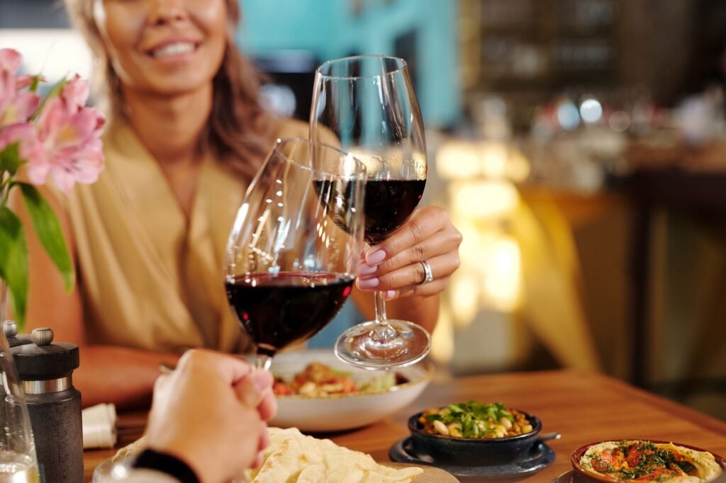 Couple toasting with red wine in a cozy restaurant setting, creating a romantic atmosphere.