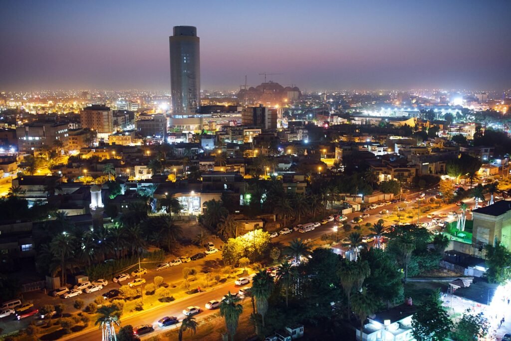 A breathtaking aerial view of Baghdad's skyline at night, showcasing illuminated buildings and bustling streets.