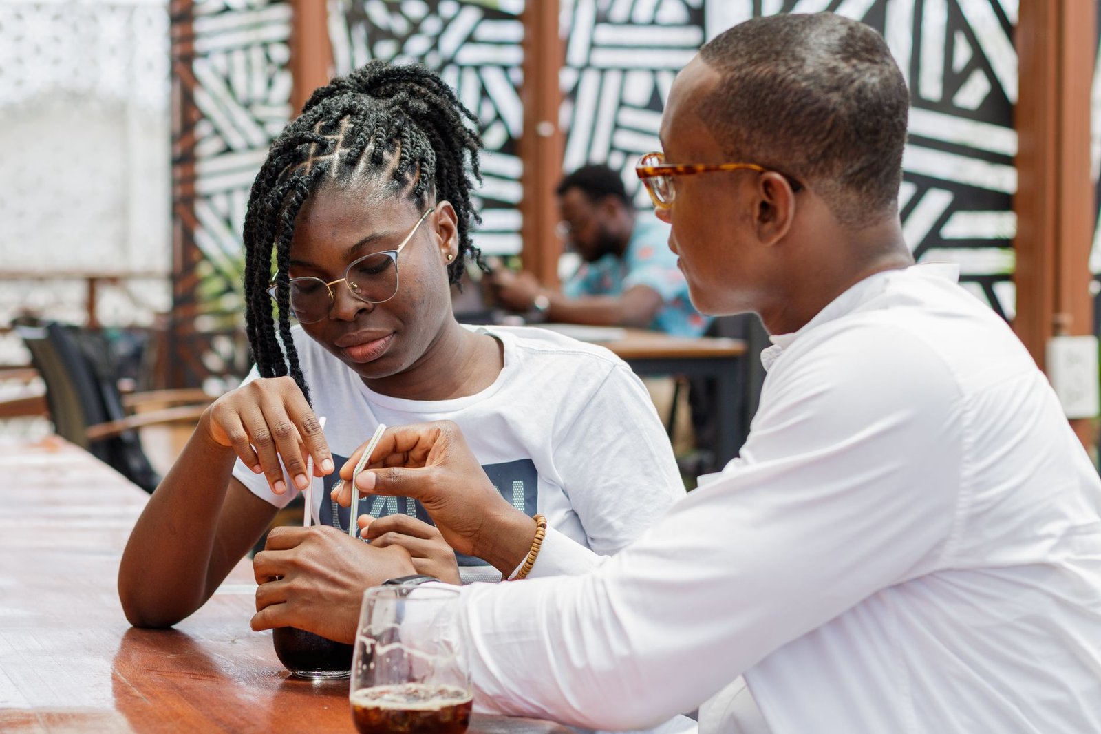 Two adults in polite conversation at an outdoor table in a Ghanaian town