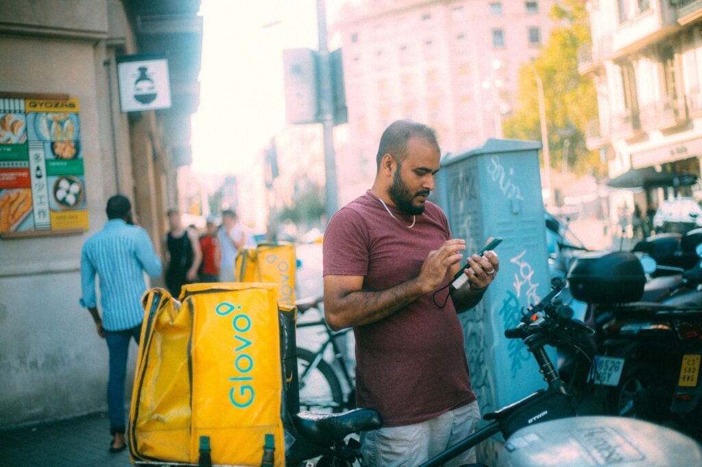 A person checking their phone at a discreet street-side meeting point in the evening