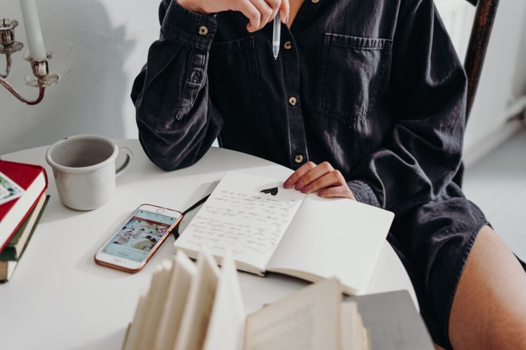 A smartphone and notebook on a wooden table in soft afternoon light