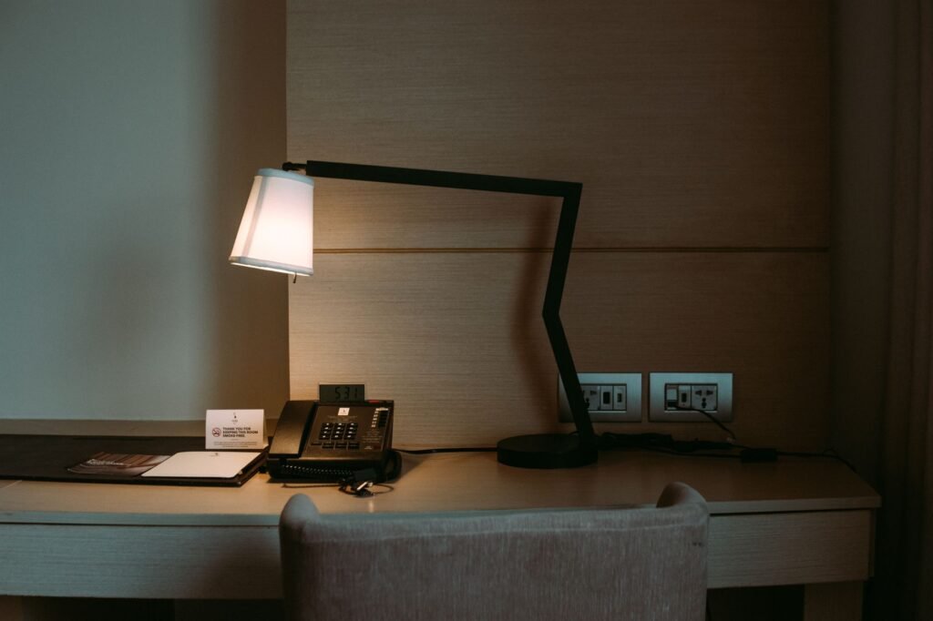 A mobile phone and small bag on a bed in a simple hotel room in daylight