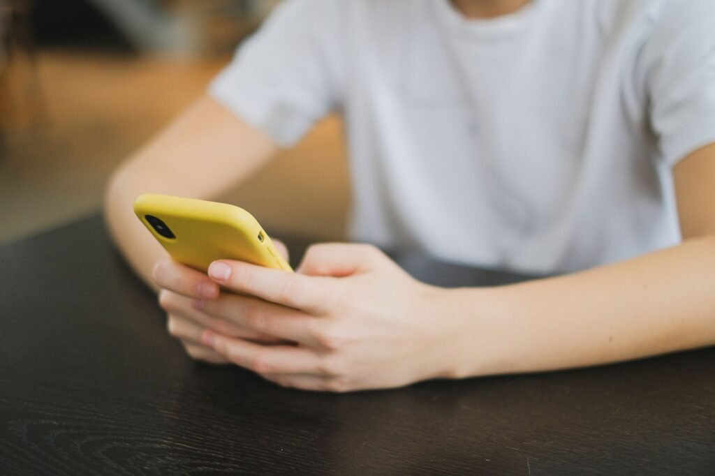 Person composing a polite message on a smartphone at a wooden table