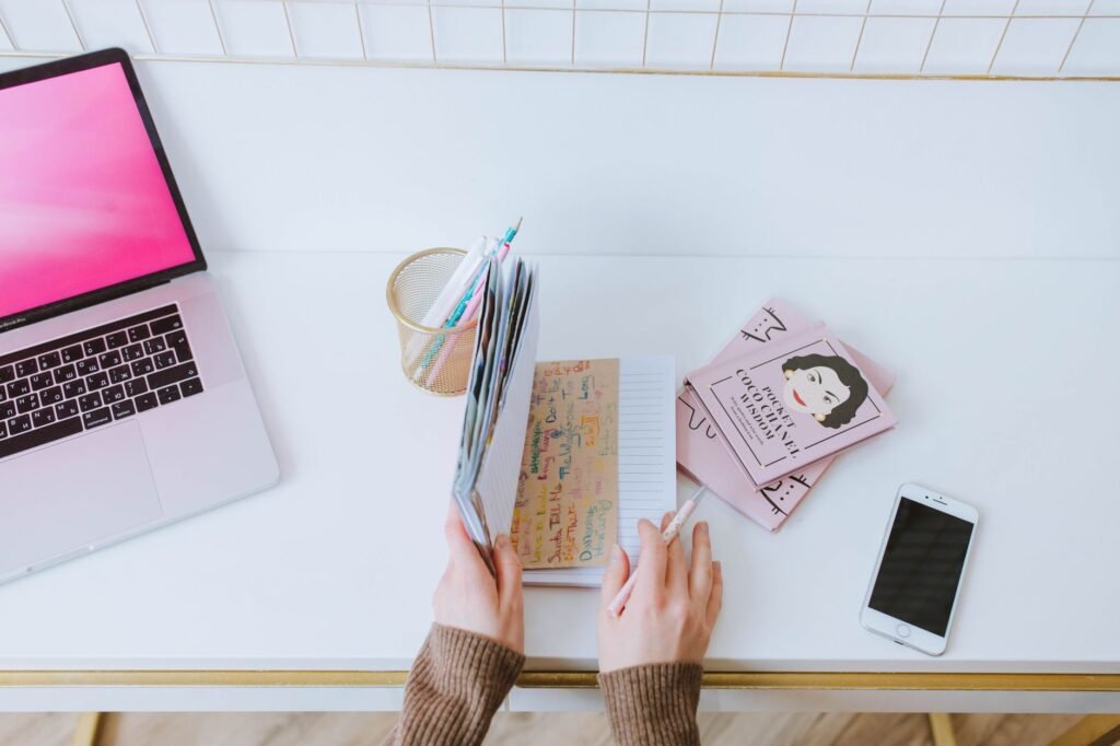 A smartphone and notebook on a wooden table, ready for planning a booking conversation