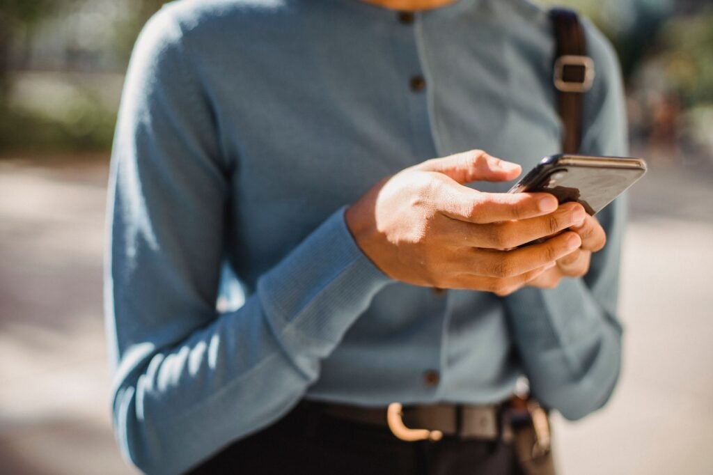 Hands typing a polite first message on a smartphone at a wooden table