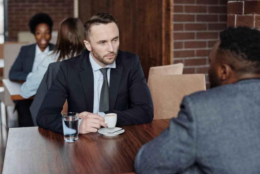 Two people in smart-casual clothing talking at a small cafe table