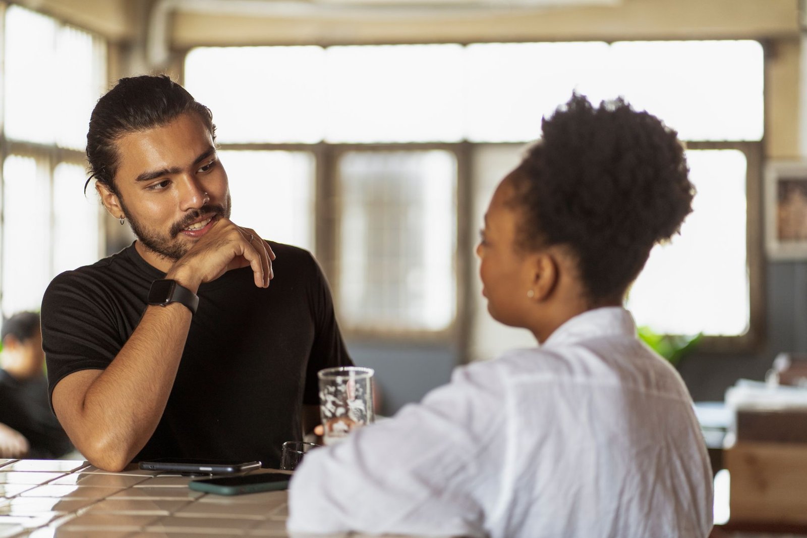 Two adults in calm conversation at an outdoor coastal cafe table