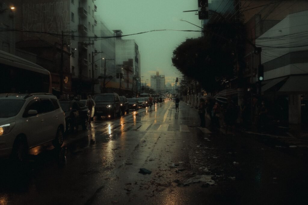 A moody evening city scene with traffic congestion on a wet street.