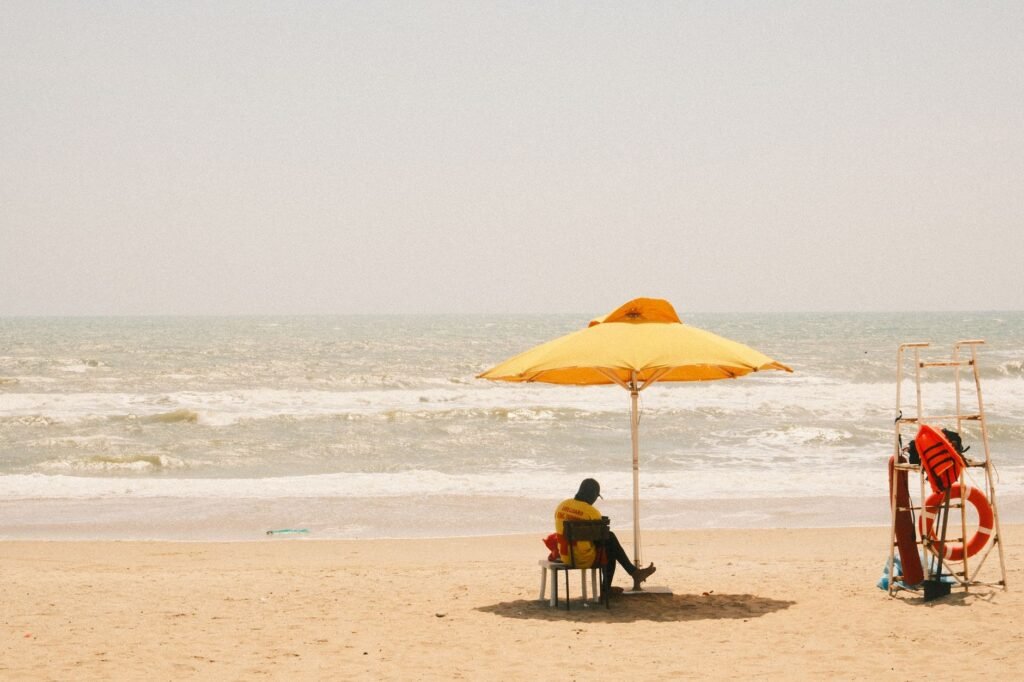 A peaceful day at Phan Thiet beach with a person relaxing under a yellow umbrella by the sea.