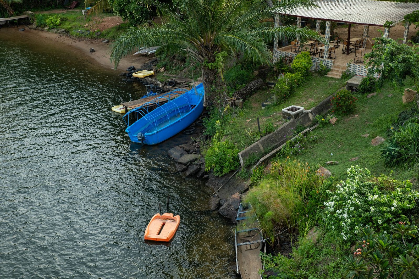 A tranquil riverside scene with boats, lush greenery, and a patio area, perfect for relaxation.