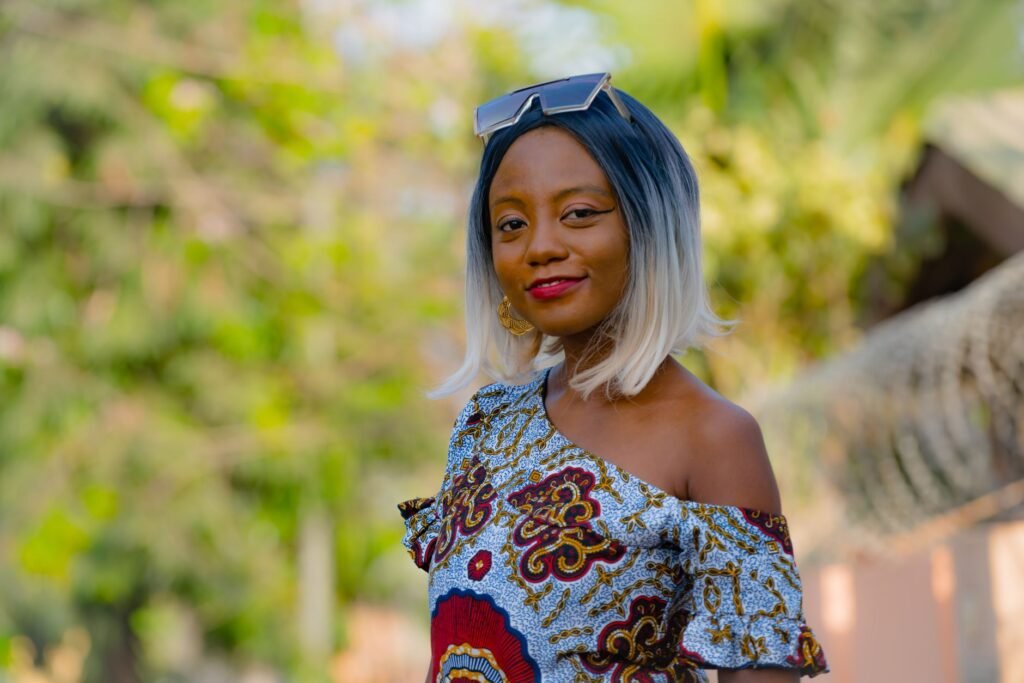 A fashionable woman smiles outdoors in Accra wearing stylish attire.