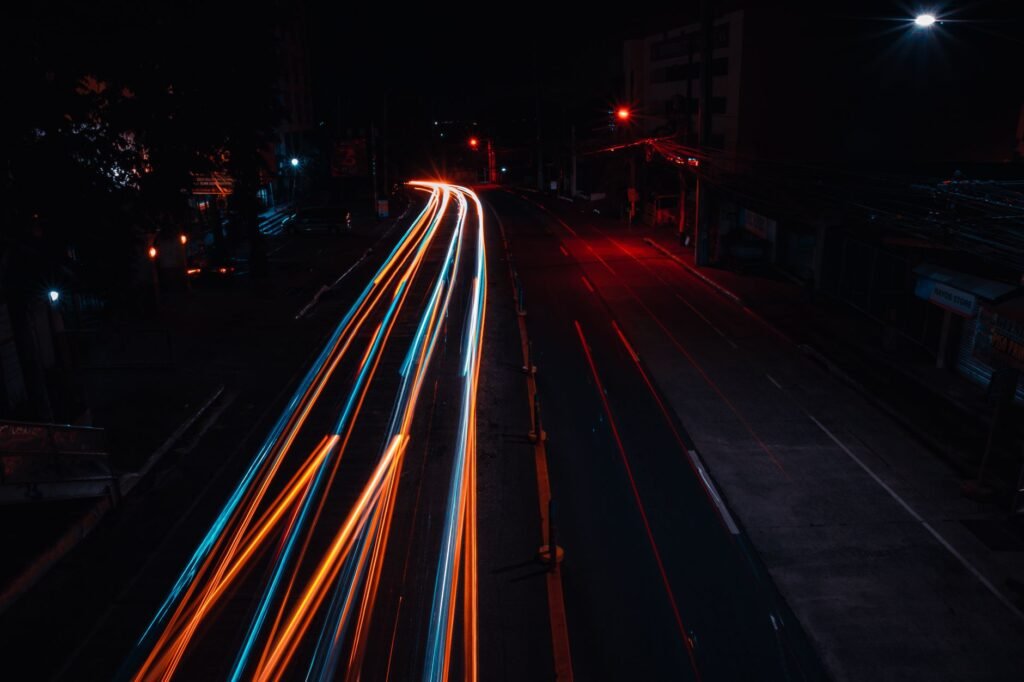 Vibrant light trails on a city street at night, showcasing urban movement and energy.