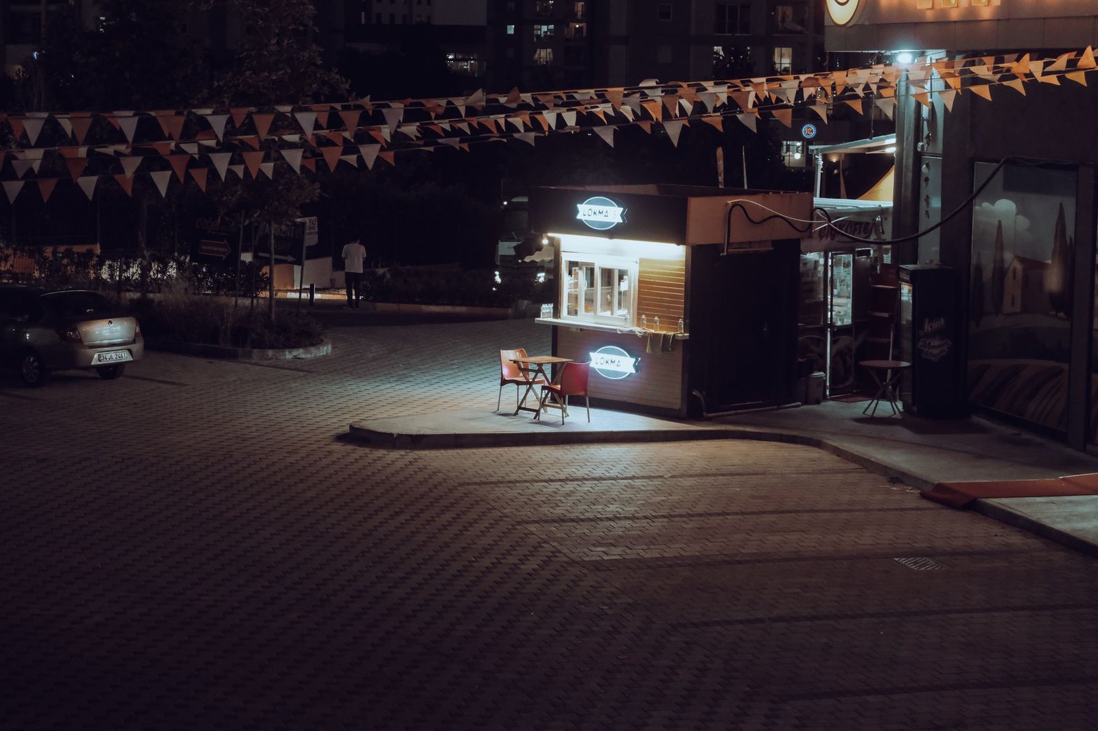 Quiet night scene of an illuminated coffee stand in an Istanbul parking lot.