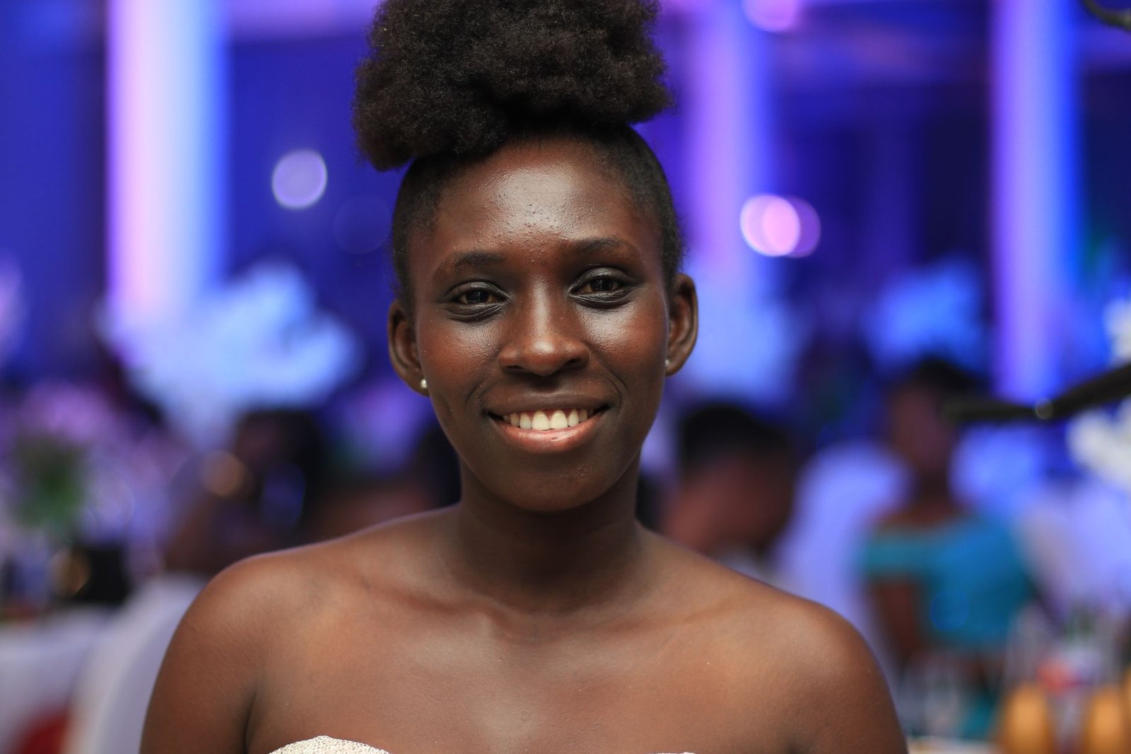 Portrait of a smiling young woman with afro hair at an indoor event in Koforidua, Ghana.
