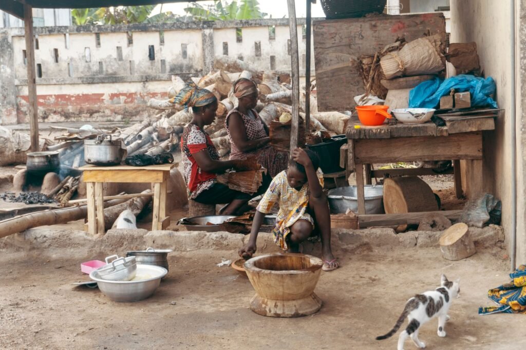 Women preparing food outdoors in Ajumako, Central Ghana, showcasing traditional African cooking methods.