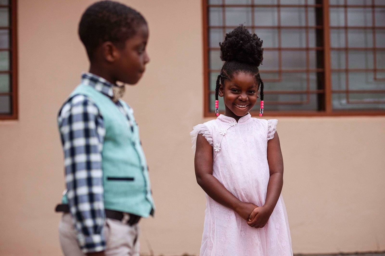 Two young children in formal clothes, smiling outdoors in Accra, Ghana.