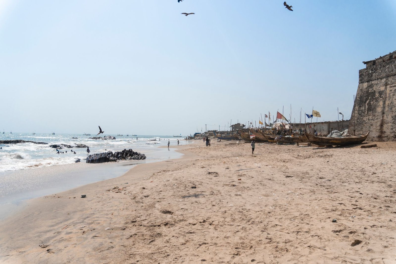 Relaxing beach scene in Ghana with boats, fort, and seashore views. Ideal for travel imagery.