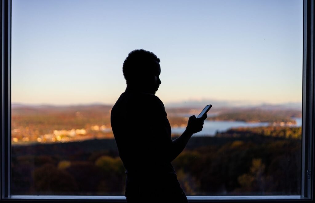 Person browsing a directory list on a smartphone by a window in natural light