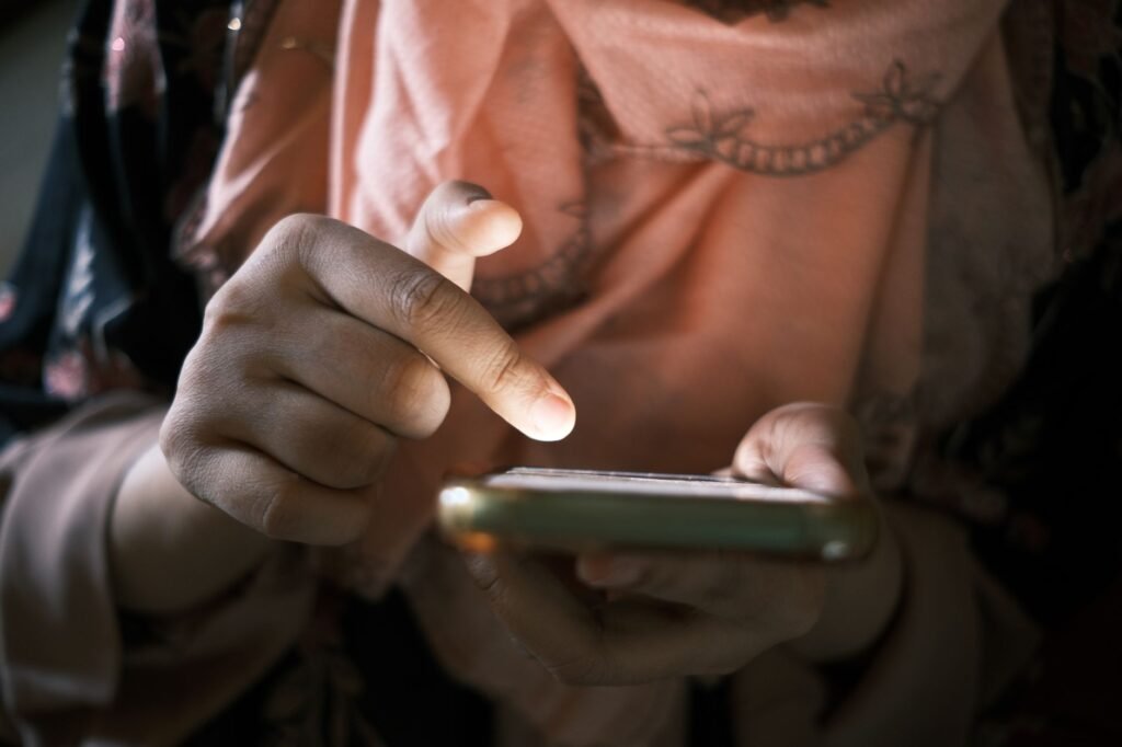Hands using a smartphone to browse a directory in a bright, simple room