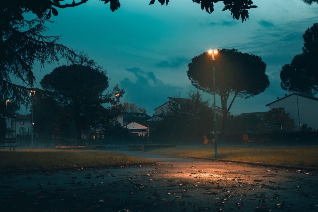 Quiet street corner in a small Ghanaian town at dusk with a bench and motorbike